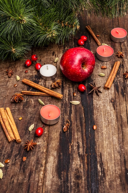 Spirito sullo sfondo di Natale. Mela fresca, cannella, rosa canina, candele, cardamomo, anice stellato.