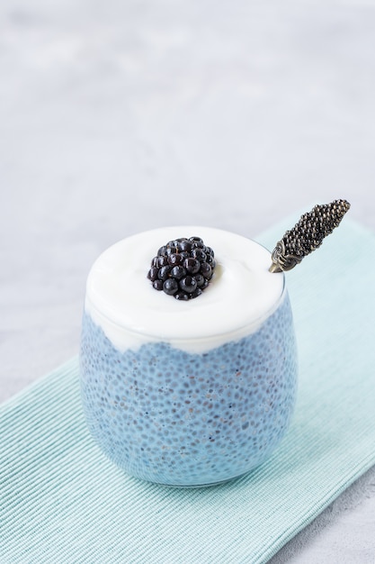 Spirulina blu o budino di semi di chia in polvere matcha blu, yogurt e mora fresca in vetro e cucchiaio. Concetto di superfood e cibo vegano. Copia spazio,