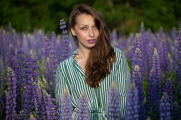 Splendida bella ragazza con magnifici capelli scuri in posa sul prato fiorito