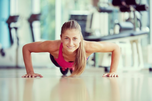 Splendida donna bionda che si scalda e fa dei piegamenti in palestra