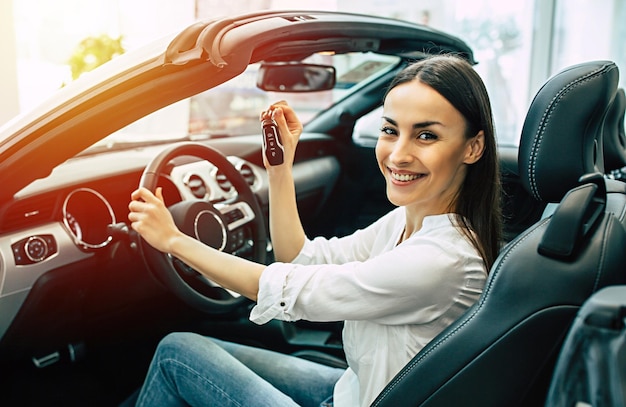 Splendida donna che acquista una nuova auto per lavoro e viaggiare in concessionaria ragazza cliente con la chiave in mano