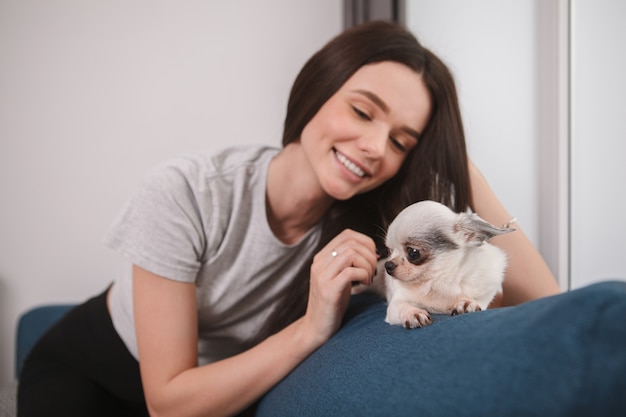 Splendida donna felice che accarezza il suo adorabile cagnolino, rimanendo a casa