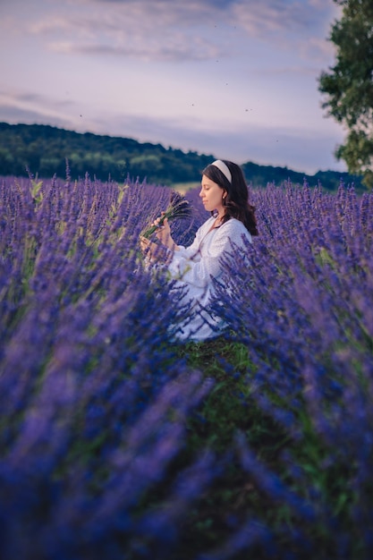 Splendida donna in abito bianco all'ora del tramonto del campo di lavanda