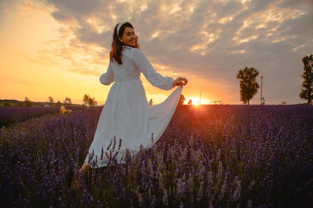 Splendida donna in abito bianco all'ora del tramonto del campo di lavanda