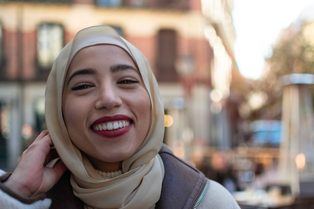 Splendida donna musulmana con sorriso a trentadue denti e sciarpa sulla testa in posa all'aperto