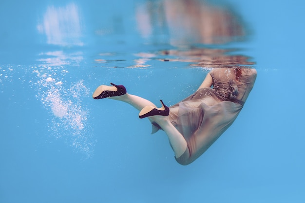 splendida giovane donna bruna con il trucco sott'acqua in piscina