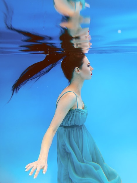 splendida giovane donna bruna con il trucco sott'acqua in piscina