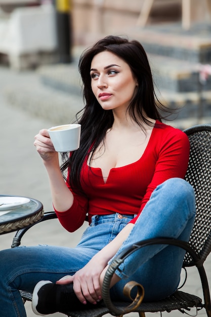 Splendida giovane donna con una tazza di caffè in città street city