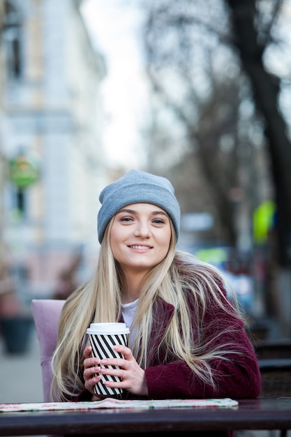 Splendida giovane donna con una tazza di caffè in città street city