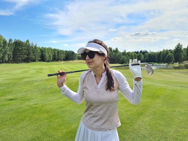 Splendida giovane donna in possesso di una mazza da golf e sorridente