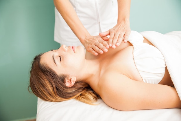 Splendida giovane donna ispanica che riceve un po' di terapia reiki in una clinica e spa. Entrambe le mani sul petto