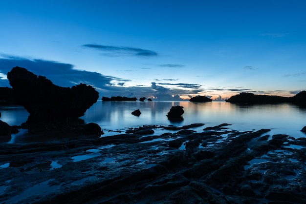 Splendida lunga esposizione di rocce costiere e mare sulla silhouette all'ora blu.