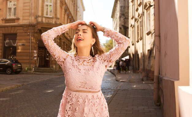 Splendida modella positiva che indossa un abito di pizzo rosa, posa nell'antica strada di Lvov L
