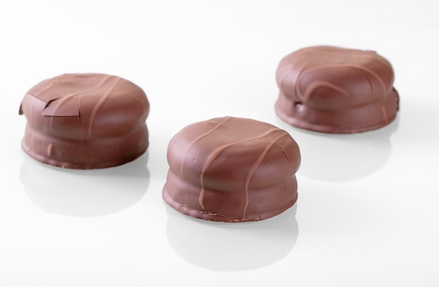 Splendida riflessione di marshmallow ricoperto di cioccolato su una superficie bianca a specchio