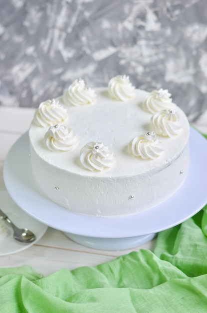 Splendida torta al biscotto delicata in crema bianca con cime di panna e perle d'argento