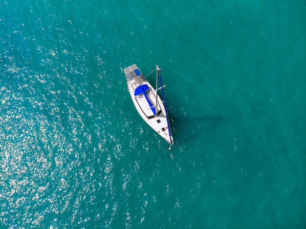 Splendida vista aerea di un enorme yacht bianco e blu che naviga attraverso la laguna blu