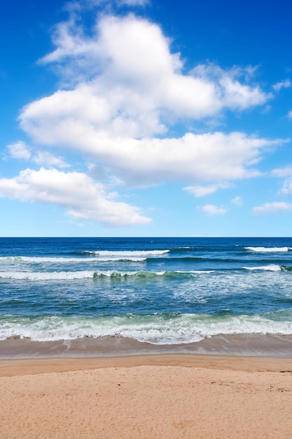 Splendida vista calma e tranquilla dell'oceano della spiaggia e del mare contro un cielo azzurro nuvoloso in una giornata estiva Oceano e mare pacifici e remoti con onde che si infrangono sulla riva in un ambiente naturale