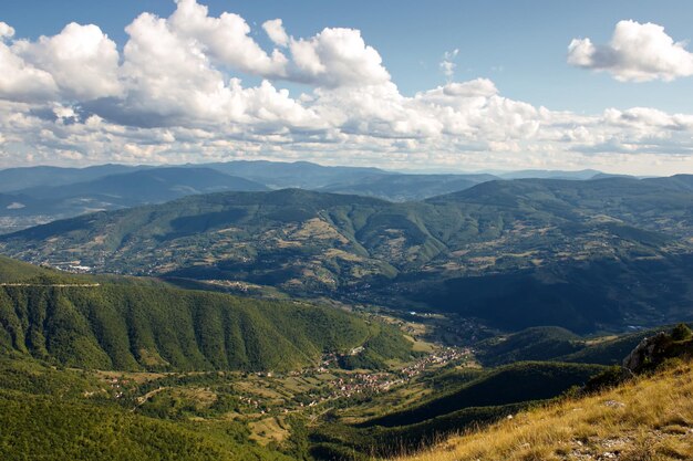 Splendida vista panoramica su un vasto paesaggio con verdi colline sotto un cielo luminoso pieno di nuvole bianche