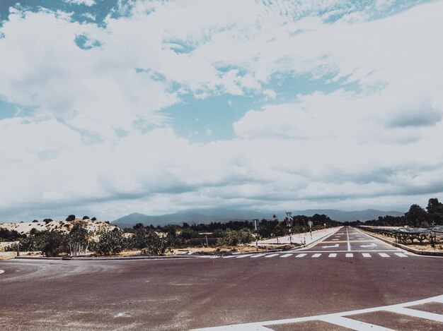 Splendida vista su un'ampia strada aperta con un'autostrada asfaltata che si estende a perdita d'occhio con piccole colline verdi sotto un cielo blu brillante nel periodo estivo Stile verde scuro