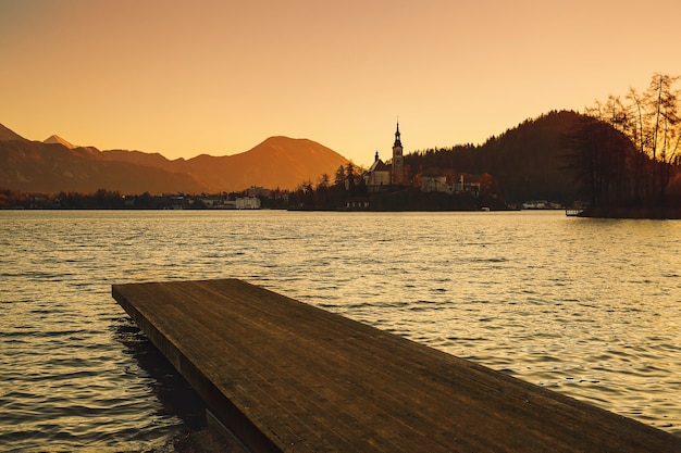 Splendida vista sul lago di Bled all'alba con molo in legno Vista sull'isola con chiesa cattolica