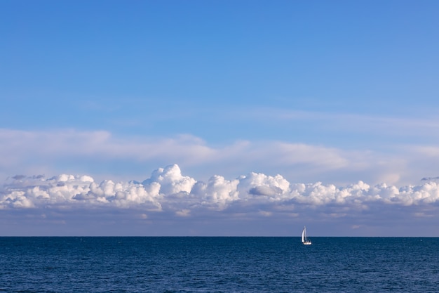 Splendida vista sul mare con barca a vela e cielo serale con nuvole testurizzate.