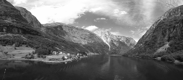 Splendida vista sulla natura con foresta verde in montagna con case di villaggio in Norvegia canale di mare acqua su sfondo blu cielo