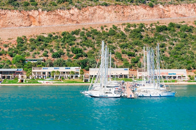 Splendide vedute dello yacht bianco del porto turistico ormeggiato vicino alla costa rocciosa verde con edifici