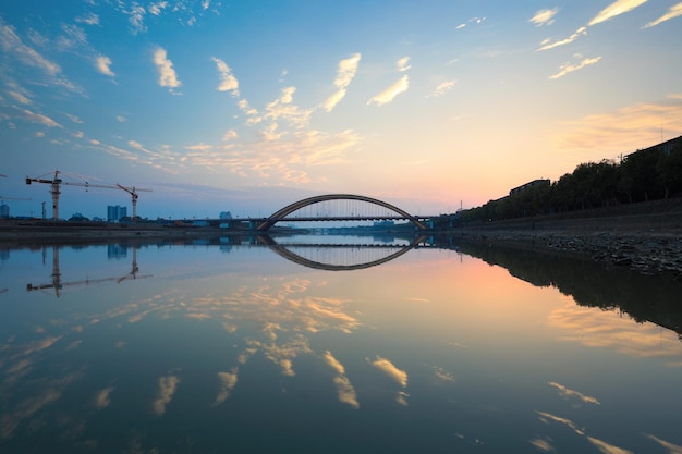 Splendido bagliore del tramonto e riflesso del ponte nel fiume