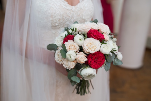 Splendido bouquet da sposa di fiori rossi e bianchi nelle mani della sposa