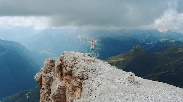 Splendido paesaggio di rocce di montagna e donna in piedi sulla cima con le braccia tese
