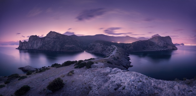 Splendido paesaggio notturno con montagne, mare e cielo stellato