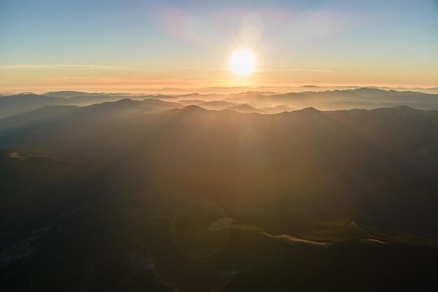 Splendido paesaggio panoramico di montagna con cime nebbiose e valle nebbiosa al tramonto