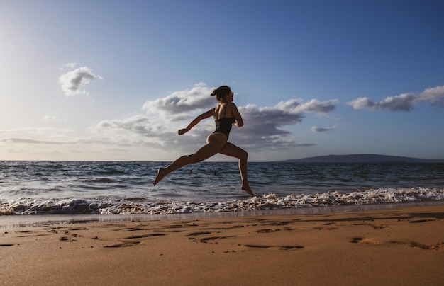 Sport all'aperto. Donna che corre lungo la riva del mare al mattino. Femmina fitness facendo esercizio in esecuzione sulla spiaggia.