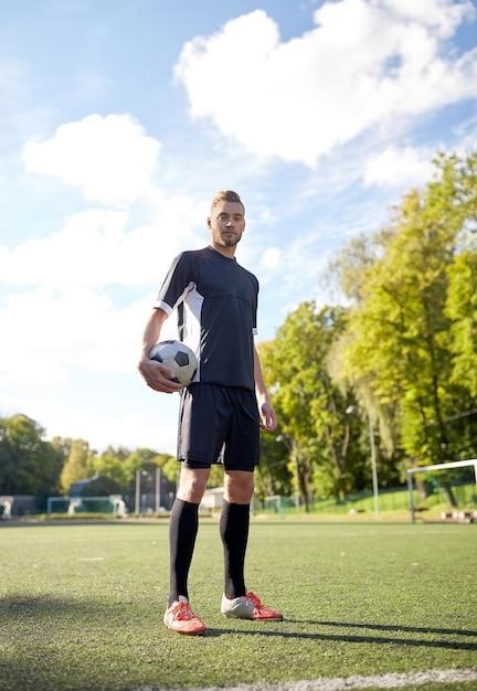 sport, allenamento calcistico e persone - calciatore con la palla in campo