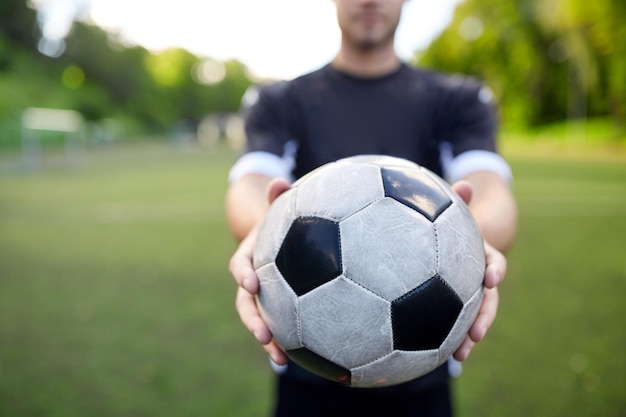 sport, allenamento di calcio e persone - mani del calciatore che tengono la palla sul campo