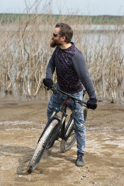 Sport brutale ragazzo barbuto su una moderna mountain bike Un ciclista in un luogo deserto di sale in riva al lago