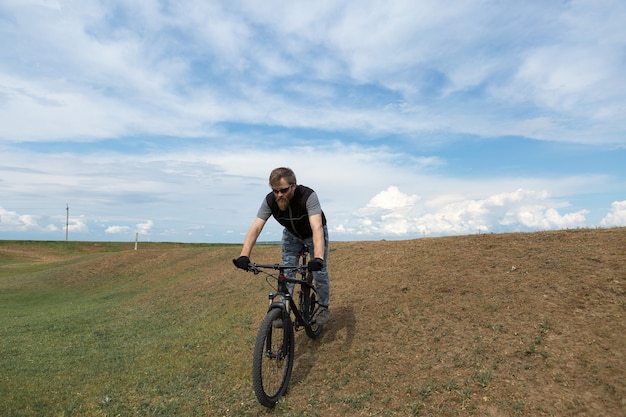 Sport brutale ragazzo barbuto su una moderna mountain bike. Un ciclista in un luogo deserto di sale in riva al lago.