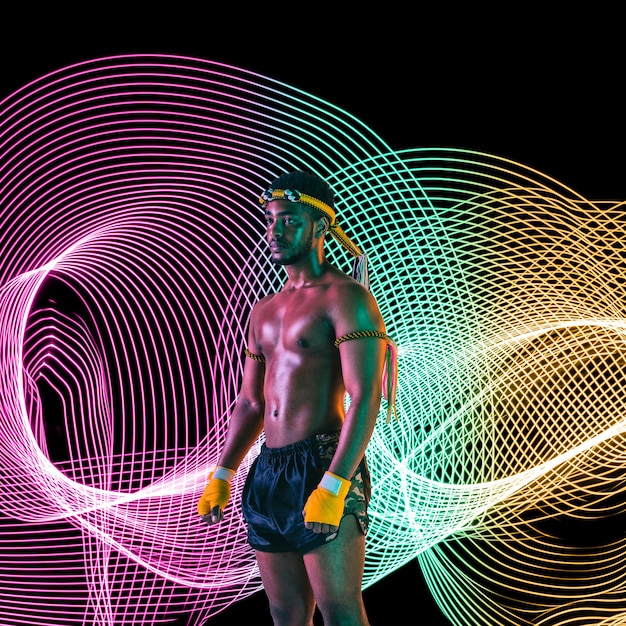 Sport creativo su sfondo di linea illuminata al neon scuro Arti marziali di allenamento muay thai in azione