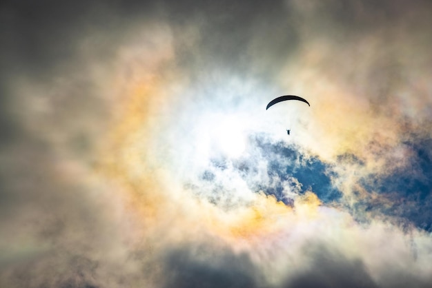 Sport d'avventura in parapendio contro il sole splendente sul cielo nuvoloso