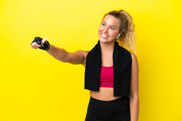 Sport donna con asciugamano isolato su sfondo giallo dando un pollice in alto gesto