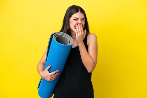 Sport Donna italiana che va a lezioni di yoga isolata su sfondo giallo felice e sorridente che copre la bocca con la mano