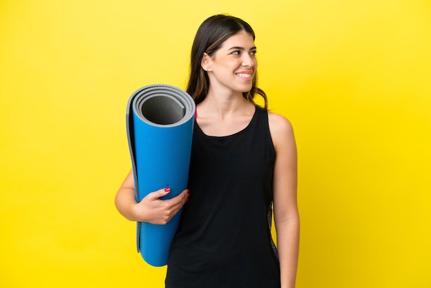 sport Donna italiana che va a lezioni di yoga isolata su sfondo giallo guardando il lato