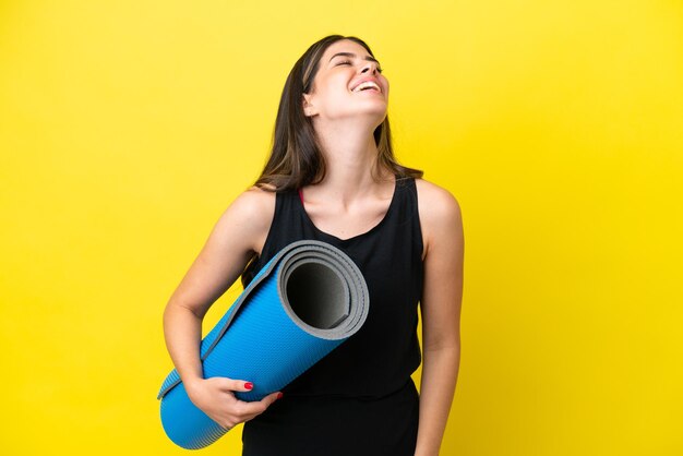 Sport Donna italiana che va a lezioni di yoga isolata su sfondo giallo ridendo