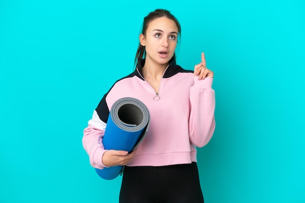 Sport Donna ucraina che va a lezioni di yoga mentre tiene un tappetino pensando a un'idea puntando il dito verso l'alto