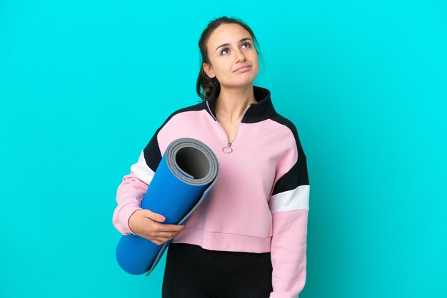 Sport Donna ucraina che va a lezioni di yoga tenendo un tappetino e guardando in alto