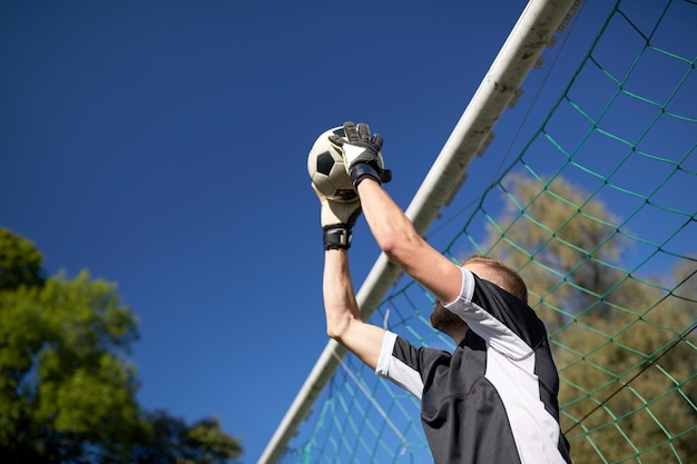 sport e persone - giocatore di calcio o portiere che prende la palla alla porta del calcio sul campo