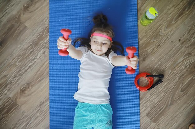 Sport e stile di vita sanoBambino che pratica sport a casa Manubrio per tappetino yoga e corda per saltare Sfondo sportivo con esercizi domestici