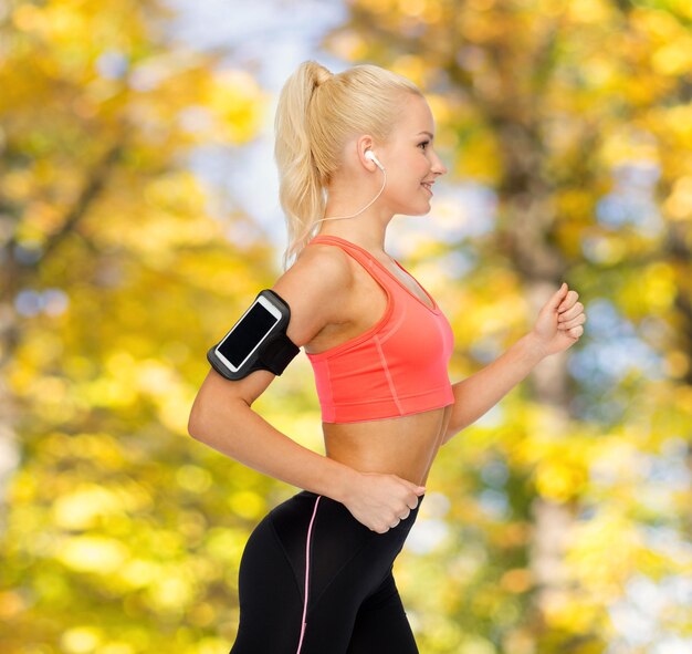 sport, esercizio fisico, tecnologia, internet e assistenza sanitaria - donna sportiva sorridente che corre e ascolta musica dallo smartphone