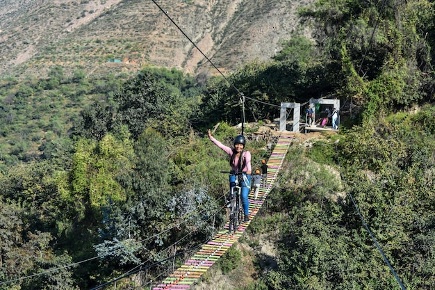 Sport estremo, giovane donna in sella a una bicicletta su un cavo di montagna in montagna