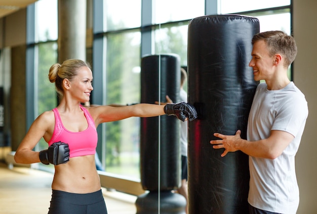 sport, fitness, stile di vita e concetto di persone - donna sorridente con personal trainer boxe in palestra